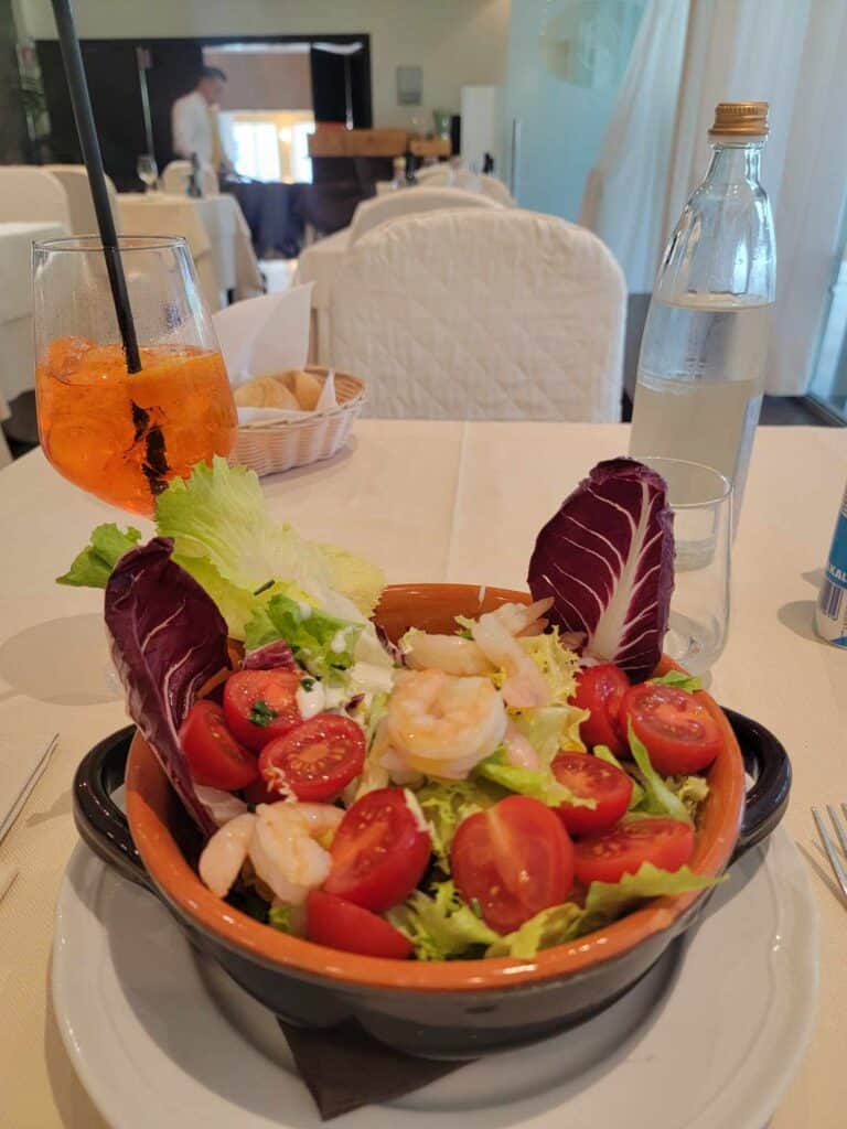 A salad with mixed greens, tomatoes, and shrimp