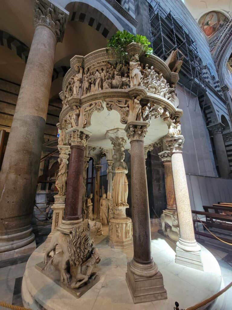 An elaborate carved white marble pulpit with lions at the base of the columns, and human figures all around