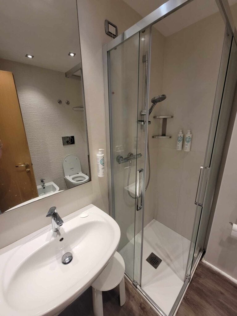 A small shower stall with glass sides, and a wide oval sink