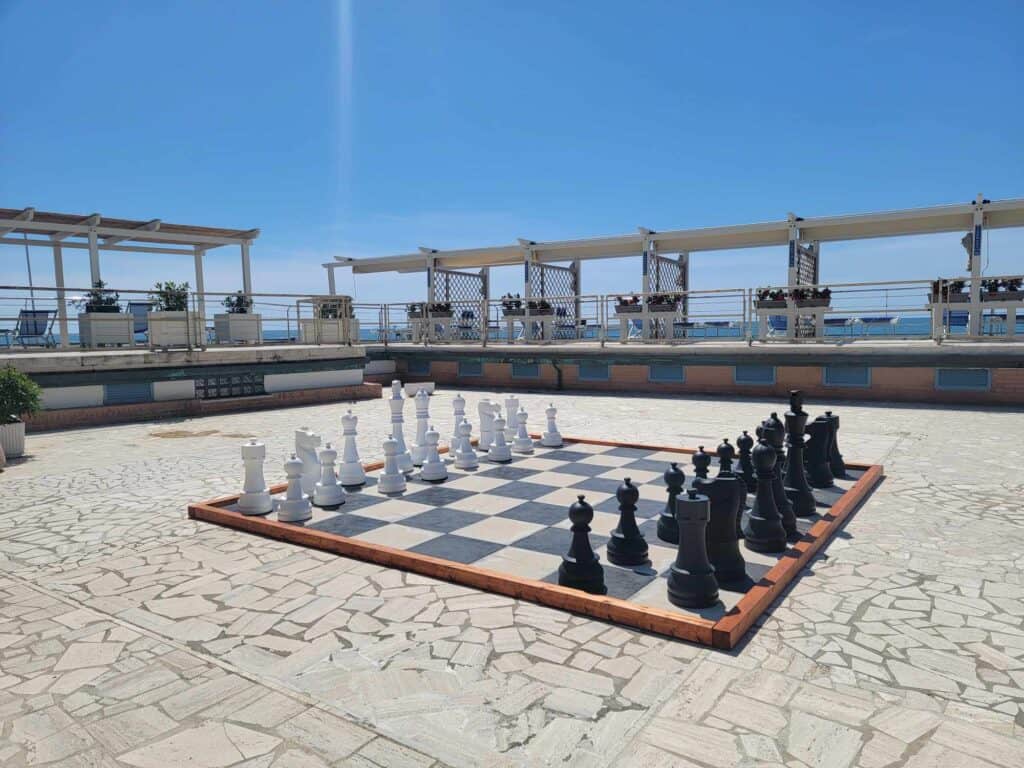 A large outdoor chess set on a patio with blue sky