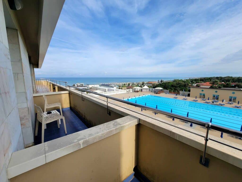 A line of balconies overlooking a large swimming pool with the ocean in the background