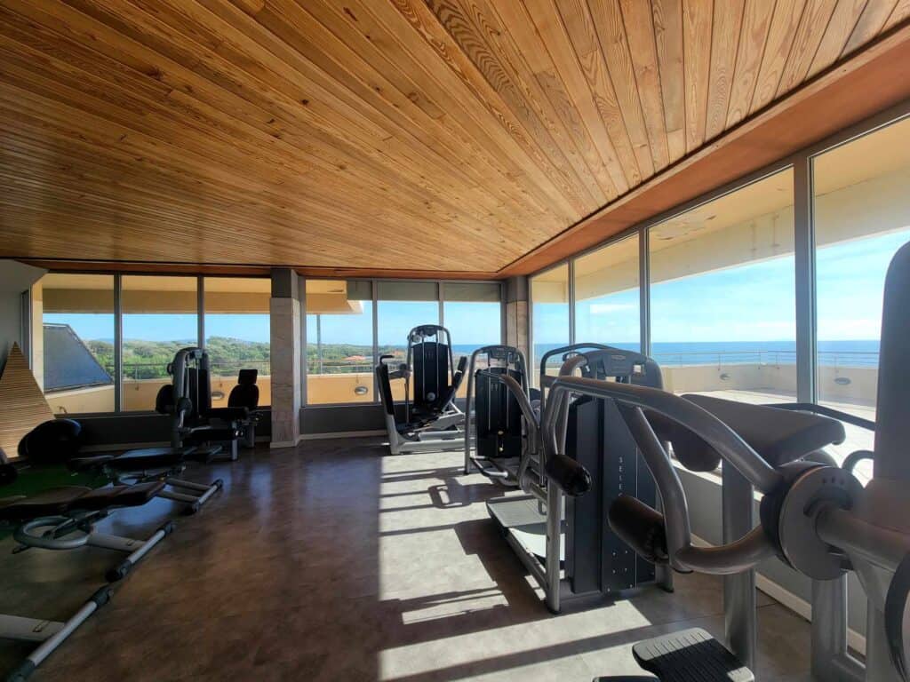 Gym equipment in a room with lots of windows overlooking the ocean