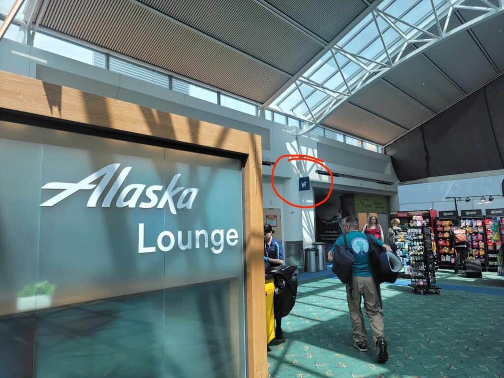 A sign that says Alaska Lounge with a pet relief area sign behind