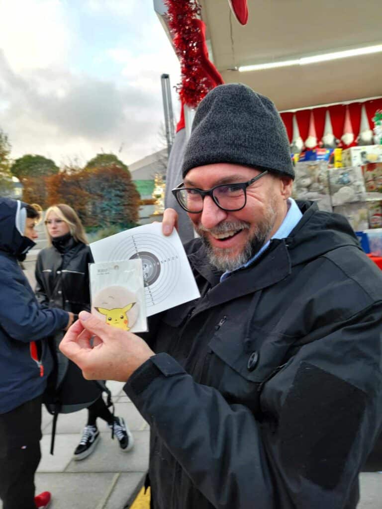 A man holding a shot-out target and a Pikachu button 