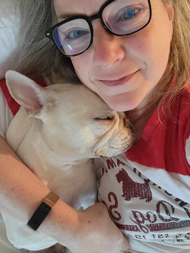 A white french bulldog sleeping on the shoulder of her mom