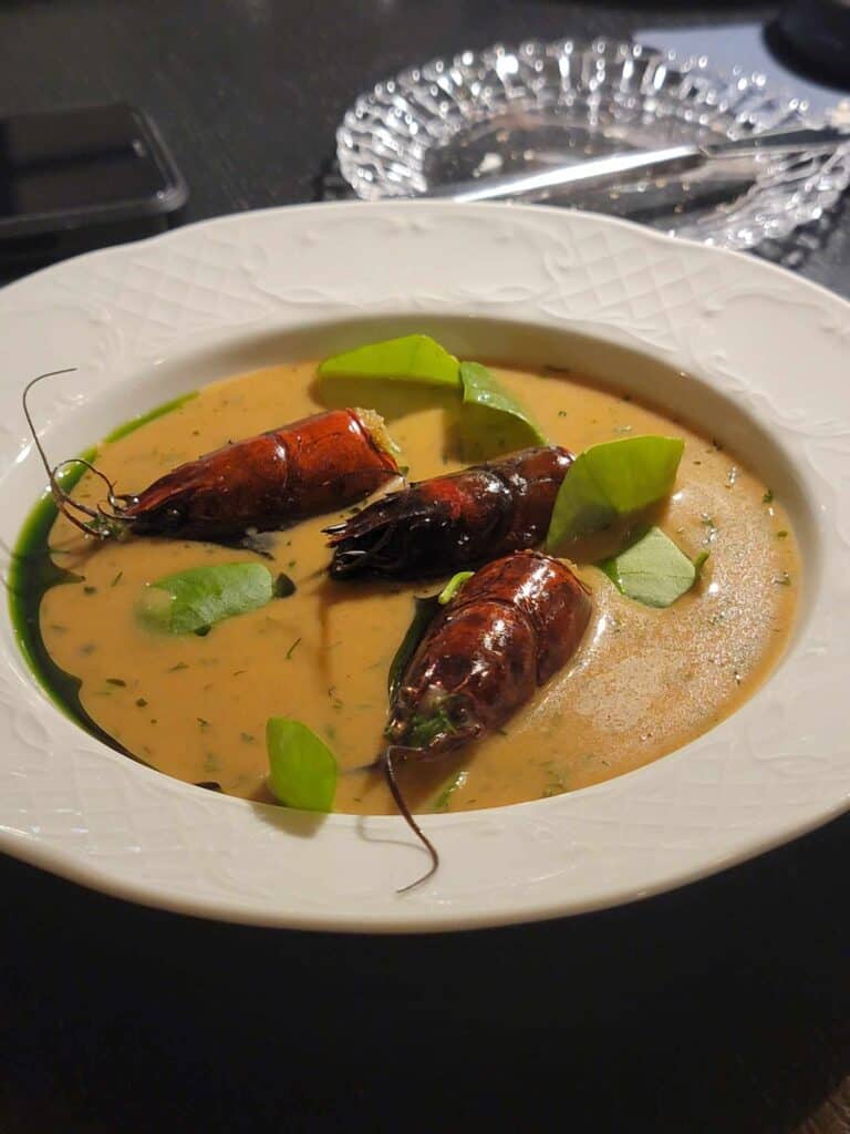 Three large langoustines peeking out of a creamy broth