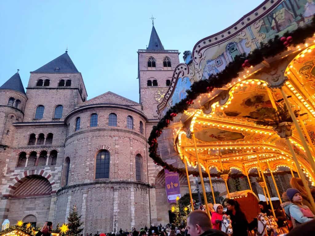 A Roman style cathedral on the left and an antique carousel illuminated on the right