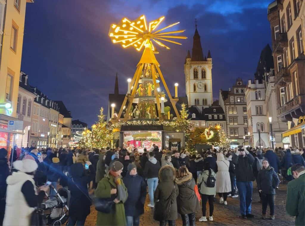 Crowds with a large illuminated Christmas pyramid and a church in the background