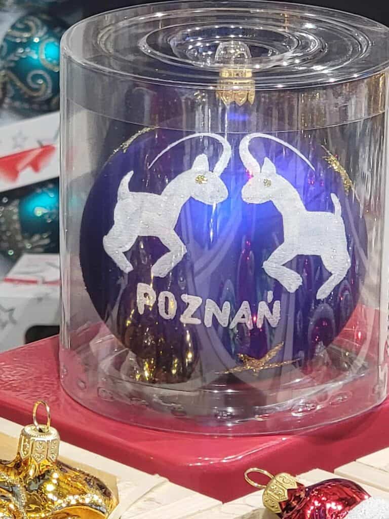 A blue Christmas ornament that says Poznan with two white goats