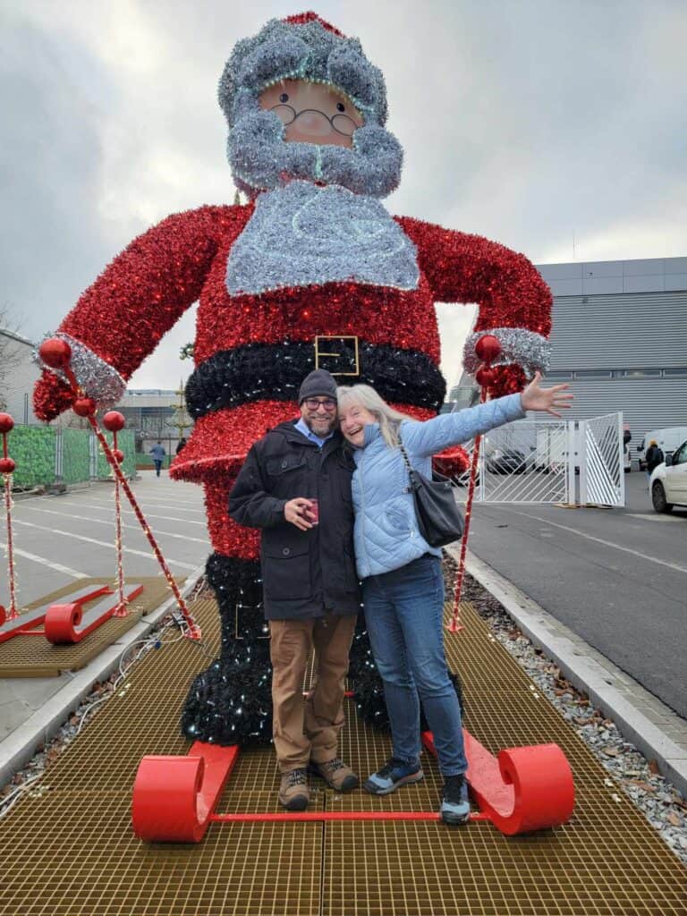 A happy couple by a huge santa on skis