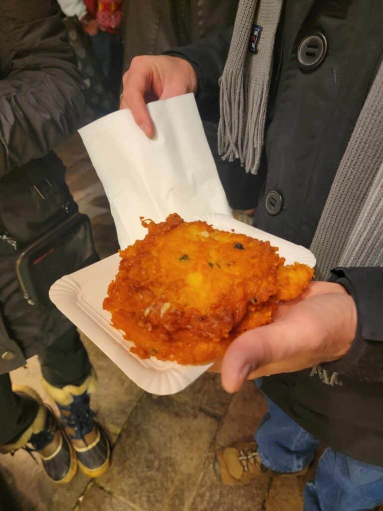 Two golden brown potato pancakes on a paper plate