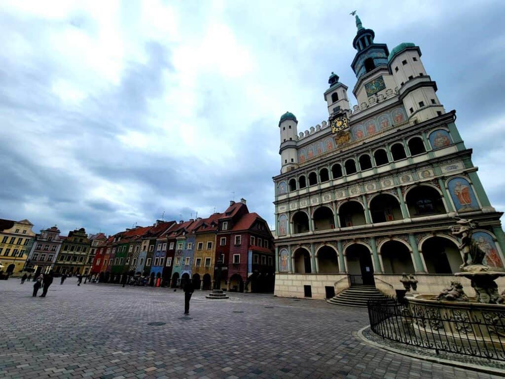 A row of connected buildings, all in bright colors and patterns with an ornate building with layers of arches and spires on top, with an intricate clock