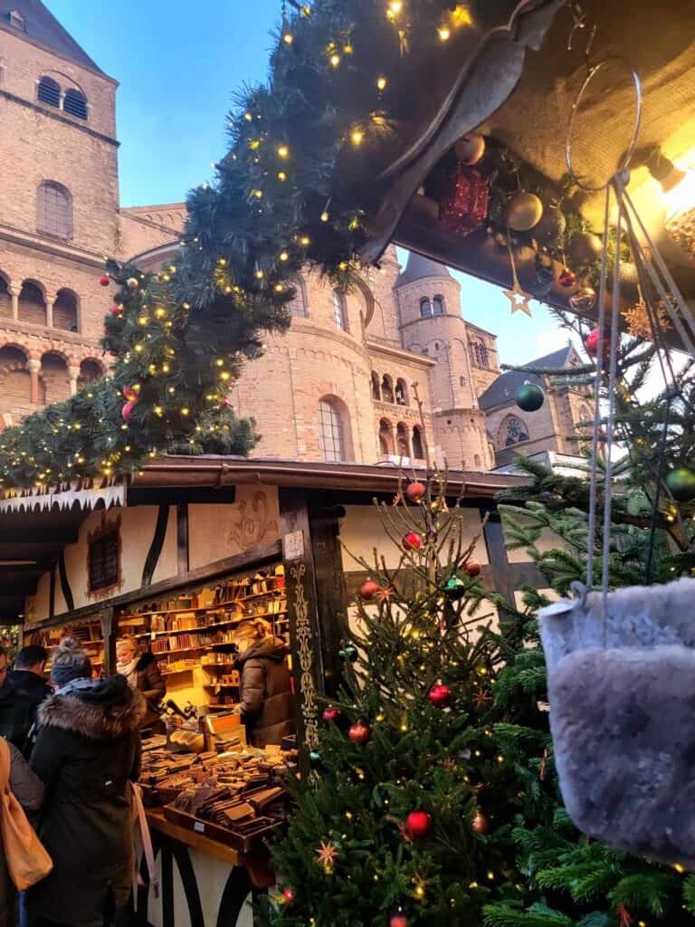 A leather goods stall with the cathedral behind and draped in illuminated garlands