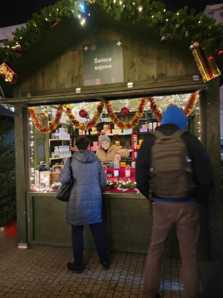 Two people at a market stall selling candles