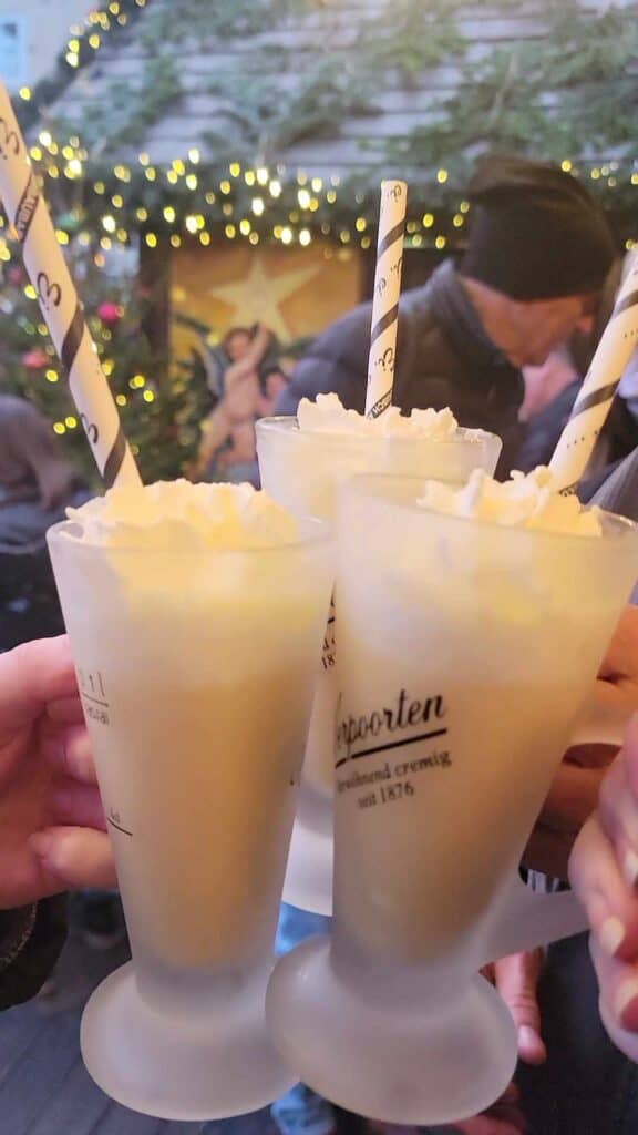 Three glasses of eierliquor with whipped cream and straws toasting