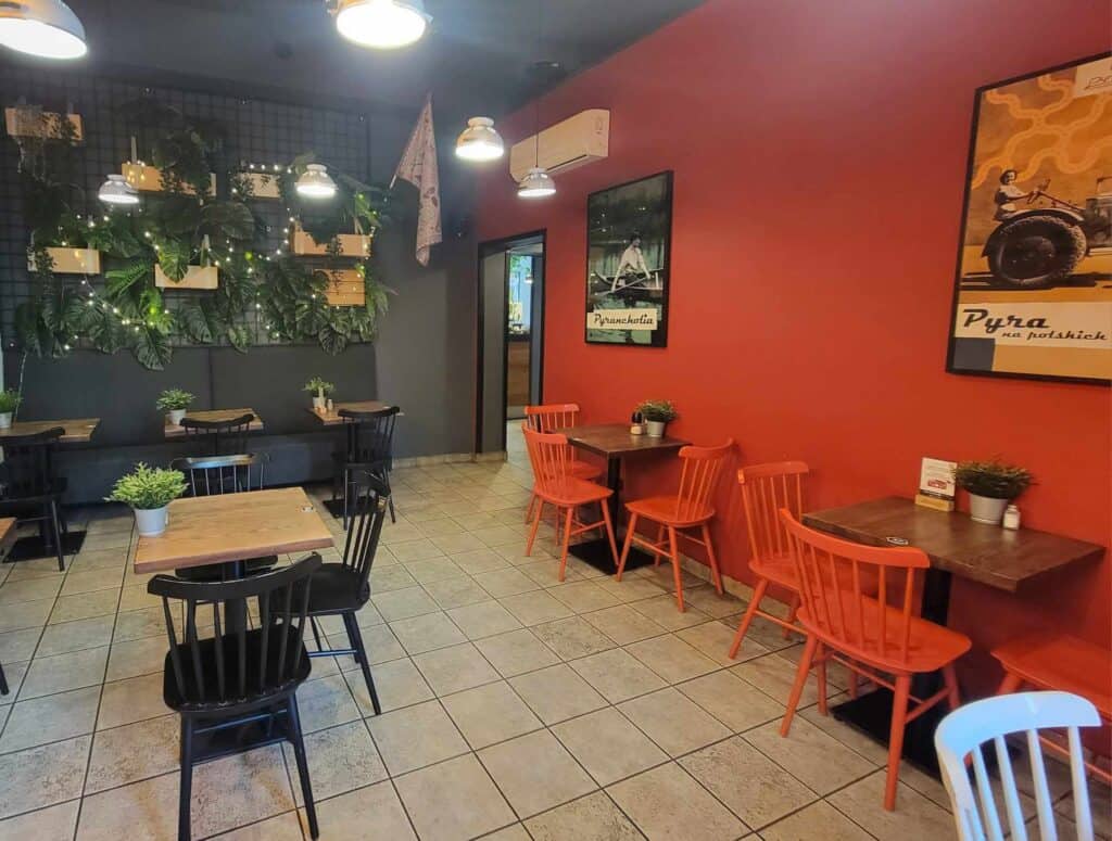 Tile floor, red and black walls with plants and lights, red and black chairs and wooden tables