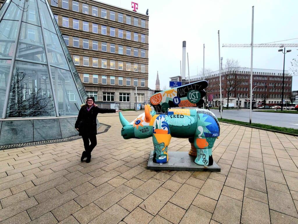 A woman touches the tip of the horn of a flying rhino sculpture