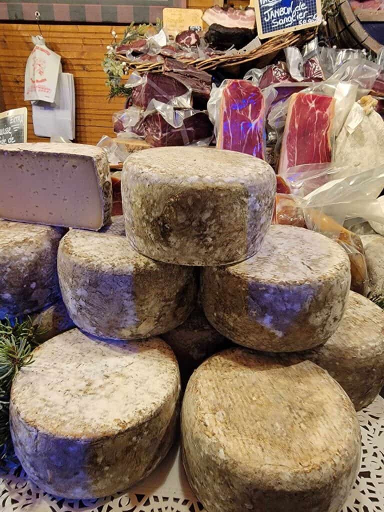 A huge stack of cheese wheels with ash-covered rinds