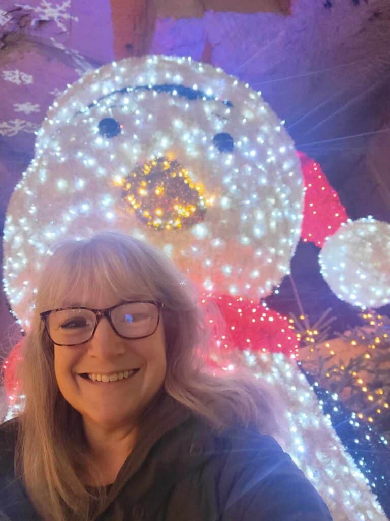 A smiling woman in front of an illuminated penguin