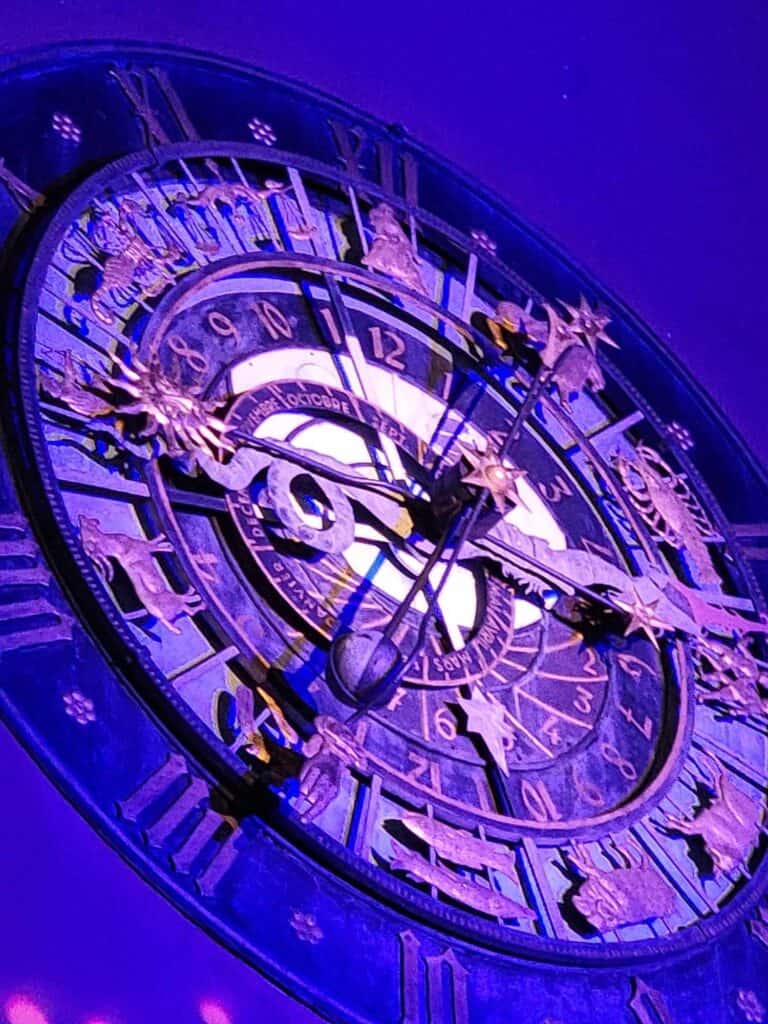 An old clock face illuminated in purple