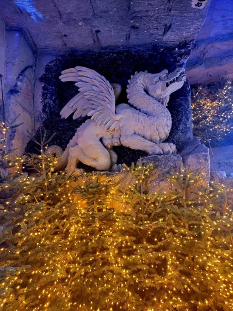 A dragon carved in limestone over a row of lighted trees