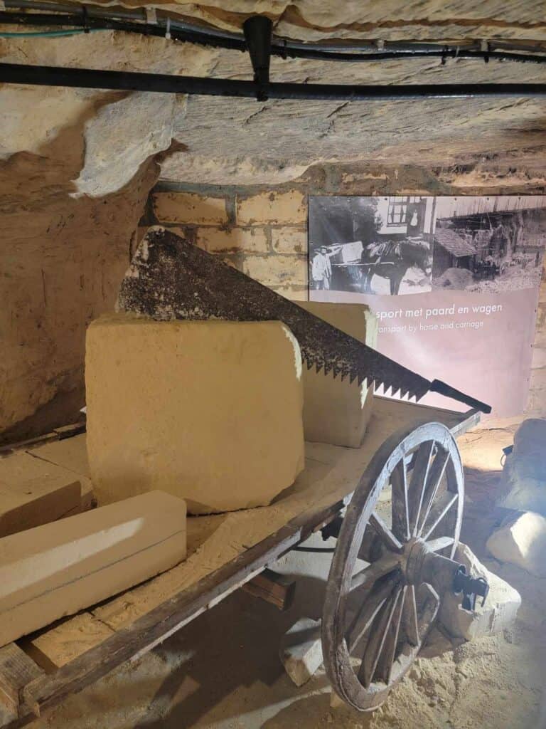 An old wooden cart in a cave with a limestone block and a saw