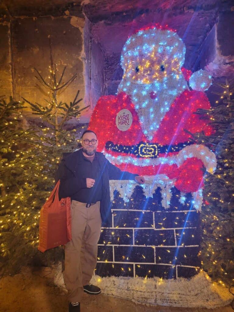 A man standing in front of a chimney with a large Santa coming out