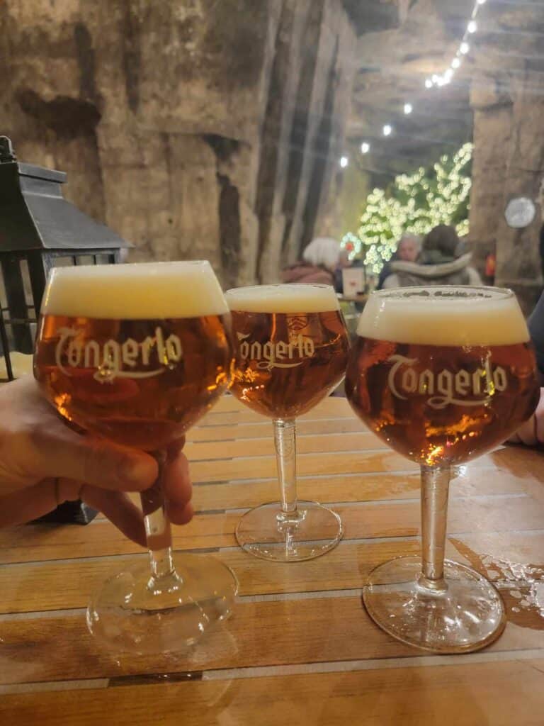 3 glasses of beer on a wooden table in a limestone cave