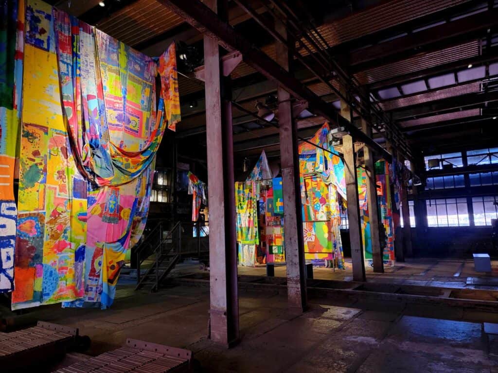 Brightly colored designs on fabric draped inside an industrial space