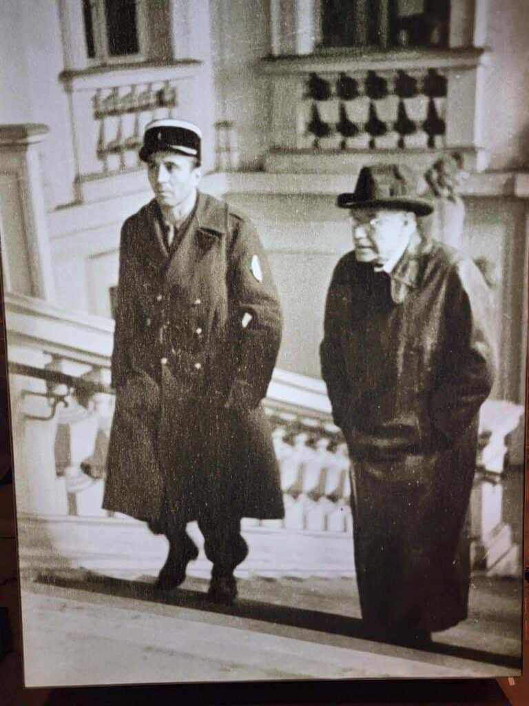 Herman Röchling walking up stairs in a stone building escorted by law enforcement