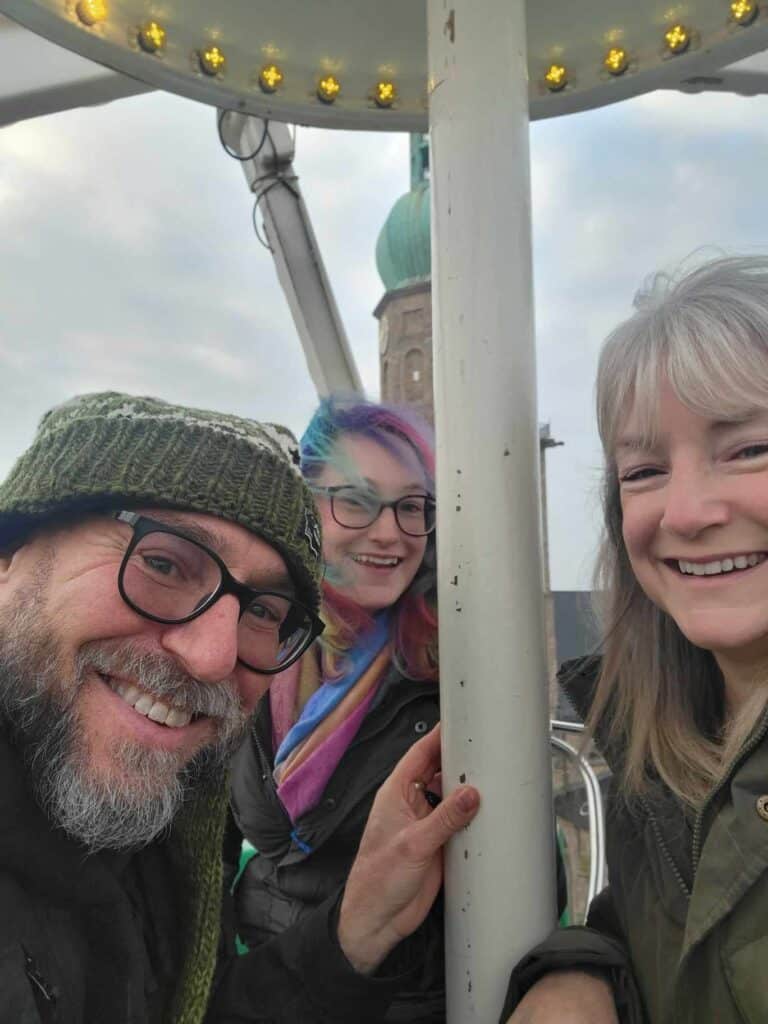 A man, a woman, and their daughter smile on a Ferris wheel