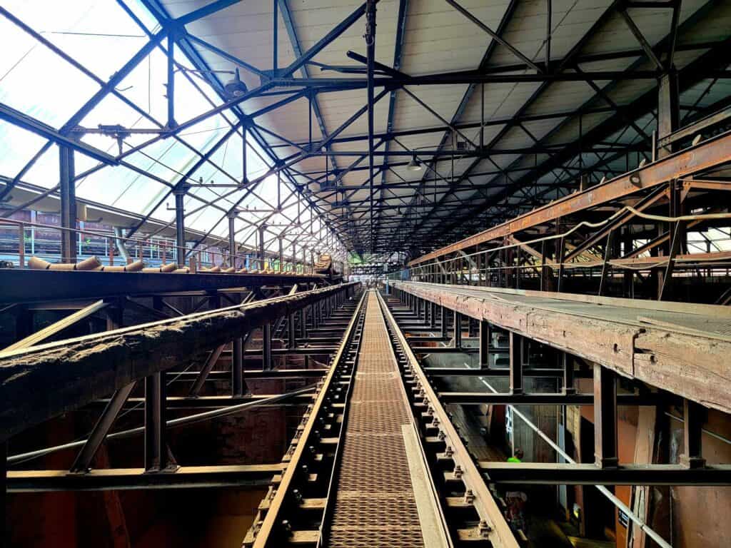 A train track under a large girdered canopy