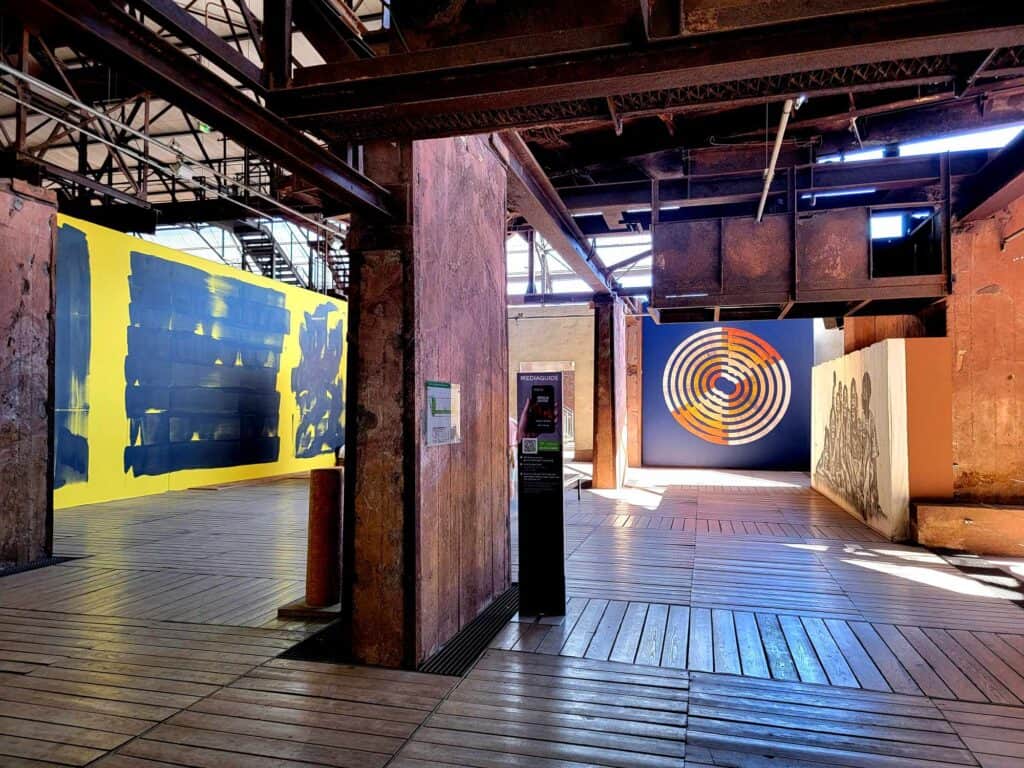 A large industrial space with a few pieces of contemporary painting