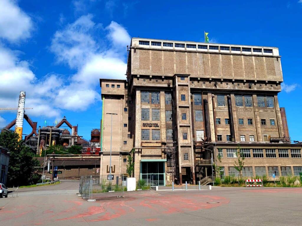 The outside of a building at the Völklingen ironworks with a blue sky and white clouds