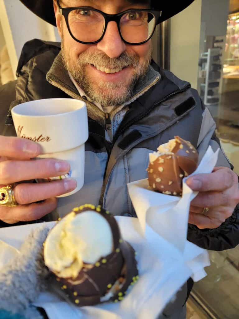 A man holding a mug that says Munster, and a chocolate covered marshmallow