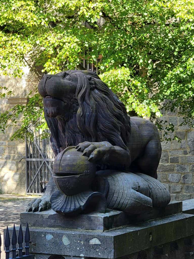 A sculpture of a stone lion on top of a very dead looking knight