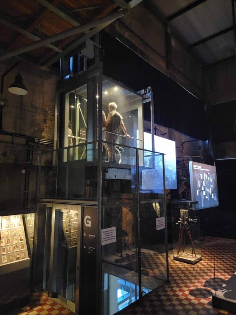 A glass elevator with a man standing and another person in a wheelchair