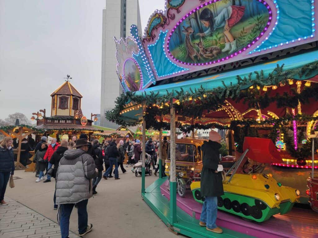 A man in a winter coat walks by a large antique carousel