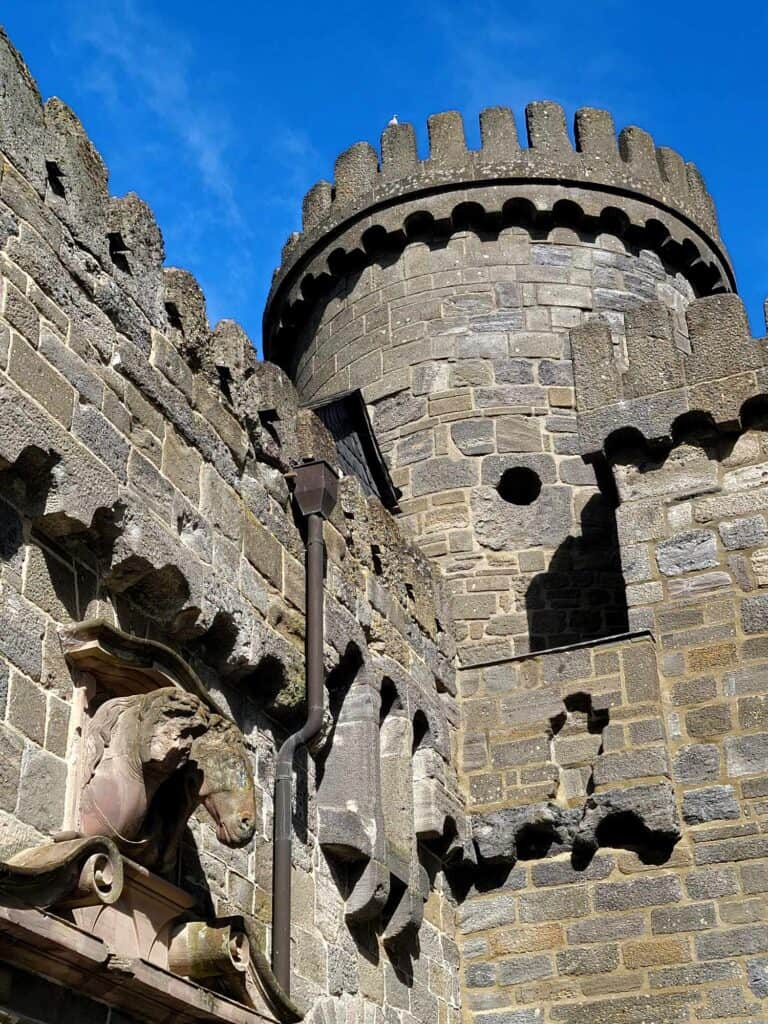 A castle tower in stone with a tower and a sculpture of a horse head