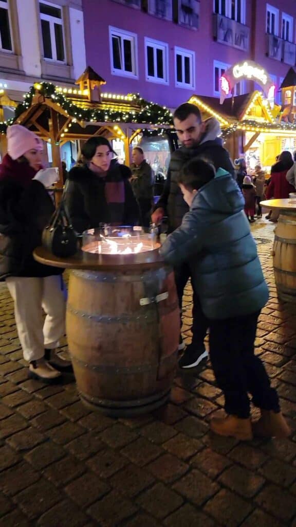 Three people around a wind barrel with a flame coming out and a tabletop