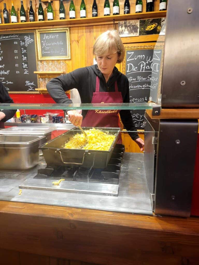 A woman stirring a large pan of spaetzele