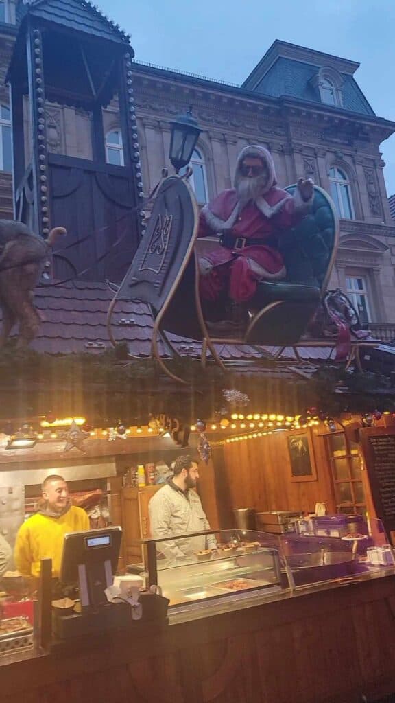 Two men in a food stall with Santa in a sleigh on the roof