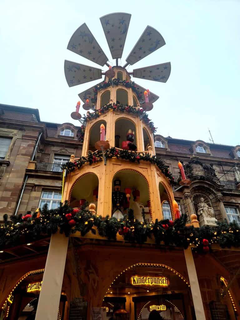 A tall Christmas pyramid with a spinning top and a gluhwein seller in the base