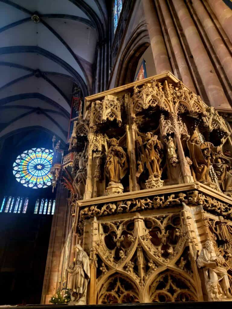 Intricate carvings in Strasbourg cathedral with the stained glass rose window behind