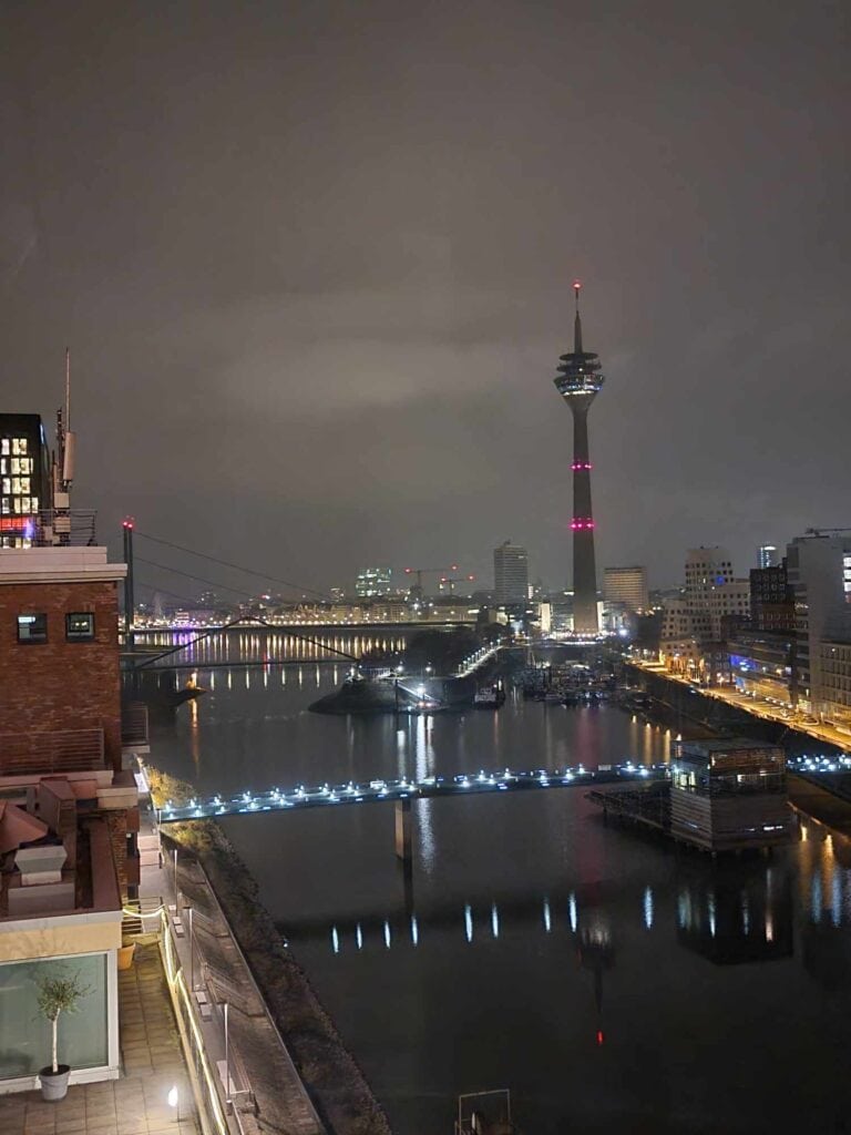 The Rhine river at night with lighted bridges and the tall Rhineturm tower on the right