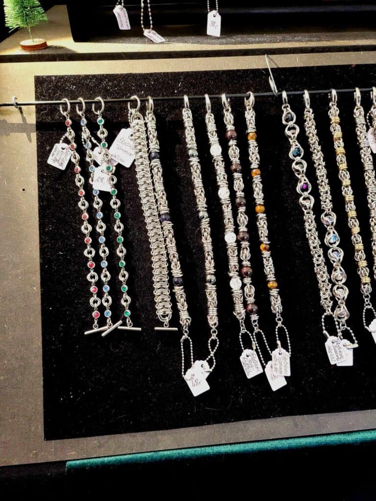 A row of woven silver bracelets with semi-precious stones