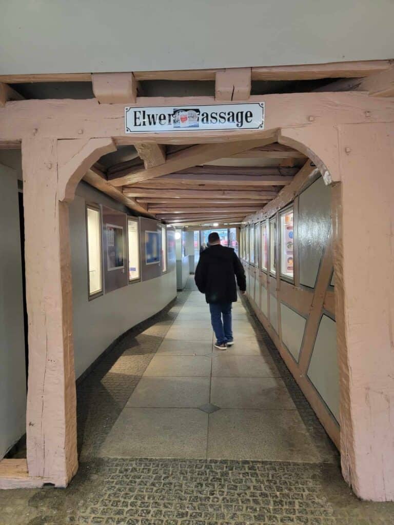 A man walks down a little tiled passageway with wooden beams on the ceiling that leads to Marburg's old town.