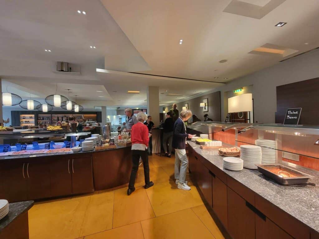 People helping themselves to breakfast from two long buffet tables