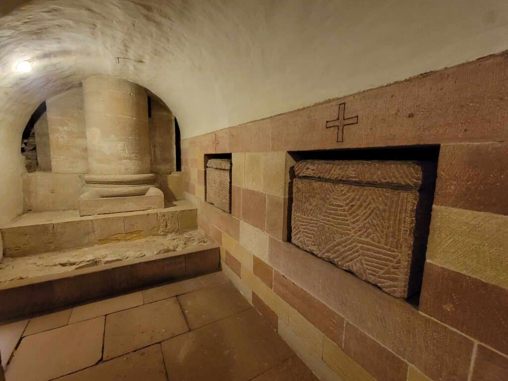 Two stone sarcophagi buried in a wall with crosses above and a sandstone floor