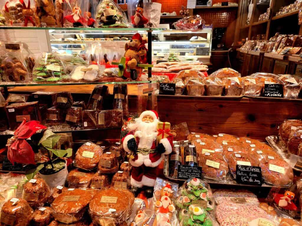 A Santa figure sits atop a pile of wrapped gingerbread and decorated Christmas cookies